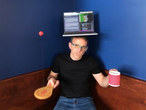 David balancing a laptop on his head while playing with a paddleball